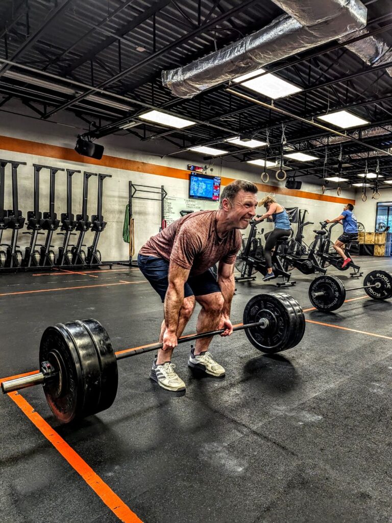 Lean, strong man deadlifting with a barbell